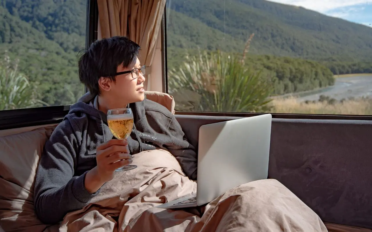 hombre Nómada digital bebiendo cerveza mientras trabaja