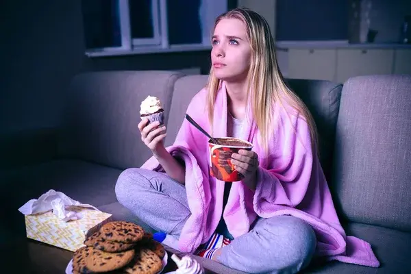 mujer joven viendo películas por la noche en su sofá 