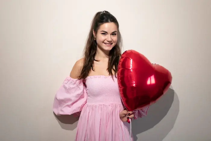 mujer linda posando junto a un globo de corazón rojo