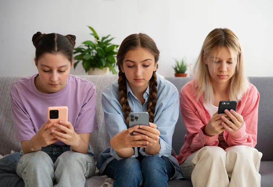 tres niñas observando sus telefonos