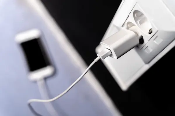 cargador conectado a un enchufe mostrando el consumo de energía de dispositivos móviles