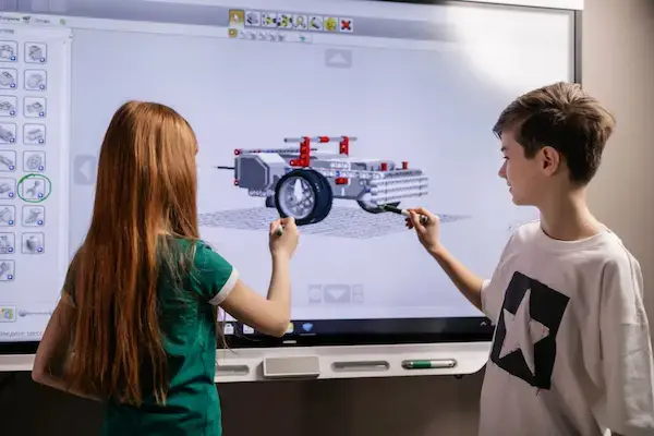 Niños diseñando un vehículo, usando tecnología de manera educativa.