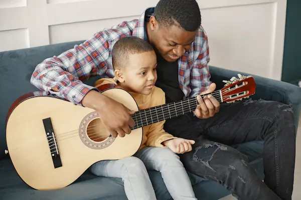 Padre e hijo aprendiendo a tocando guitarra