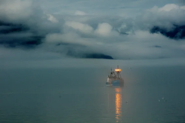 Barco iluminado navegando entre la niebla